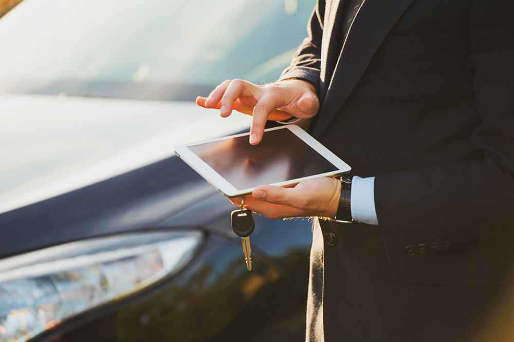 Person bedient Smartphone vor Auto